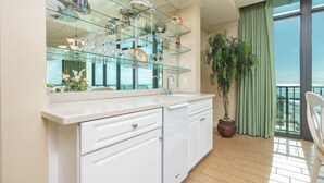 A kitchen with a glass display shelf, a potted plant, and a view of the balcony.