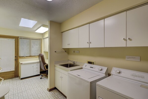 A laundry room with two washing machines, a sink, and cabinets.