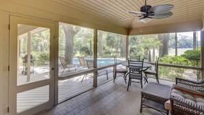 Un patio techado al aire libre con piscina, sillas y un ventilador de techo.