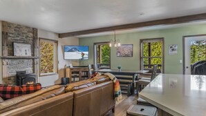 A cozy living room with a fireplace, a large sectional sofa, and a dining area with a bar. - Ski in Ski out, well appointed 4 bed, 4 bath, with hot tub and lake views! (Sandpoint)