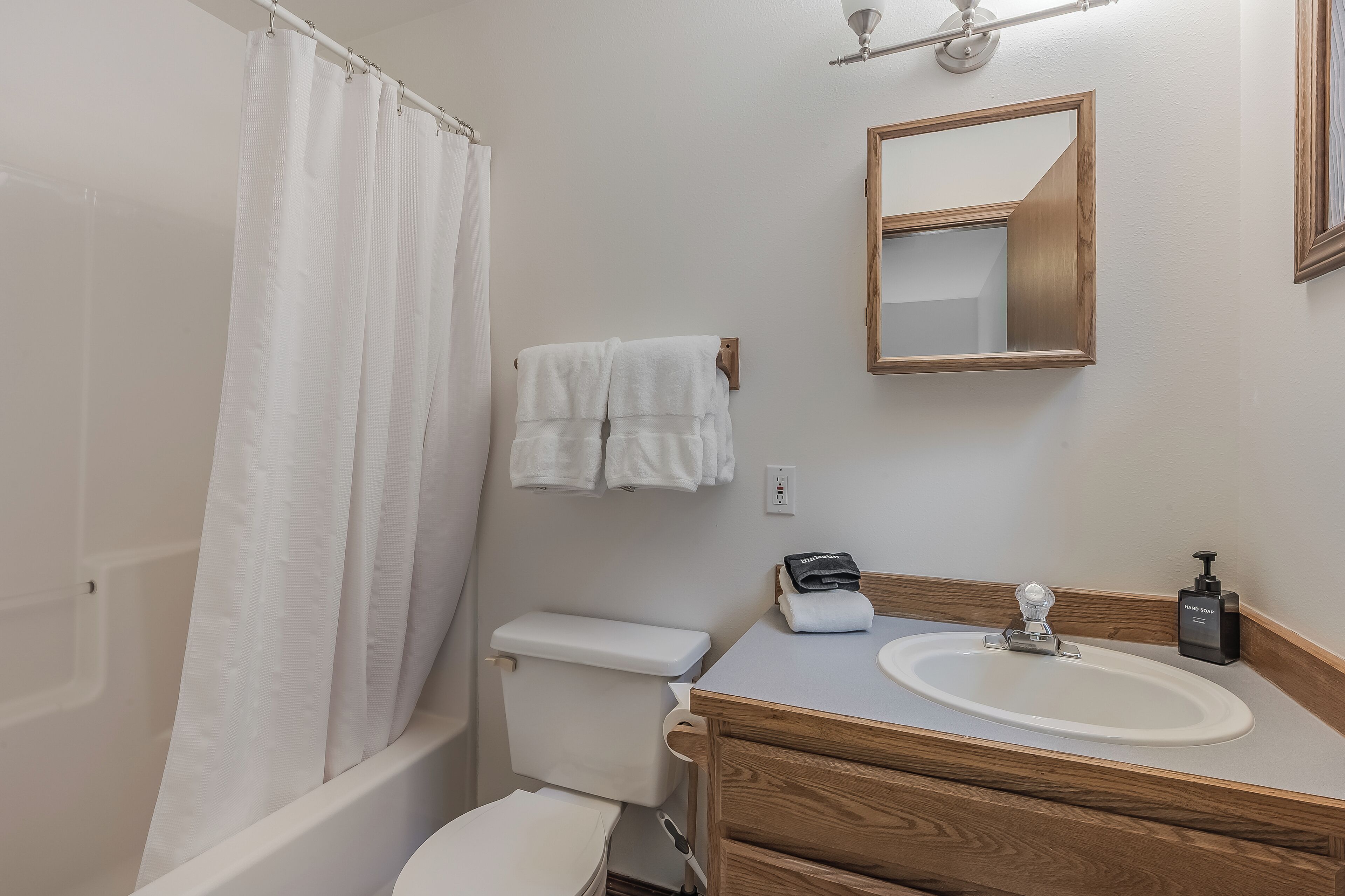 Une salle de bain équipée d’une douche, de toilettes, d’un lavabo et d’un miroir.