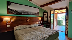 Une chambre à coucher avec un lit, des lampes de chevet, une tête de lit en bois, un tableau accroché au mur et une vue sur l’extérieur.