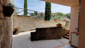 Un mur de briques agrémenté d’un pot de fleurs, un banc en pierre et une petite table en bois.