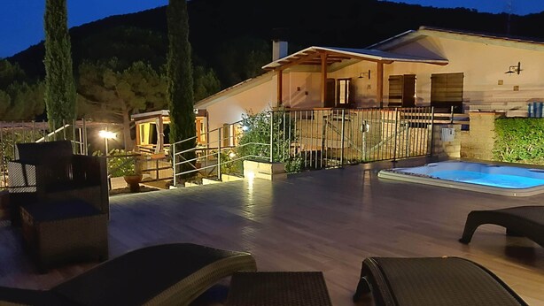 Un espace extérieur bien éclairé, doté d’une piscine, de chaises longues et d’une terrasse en bois.