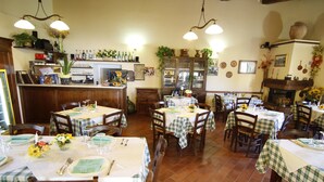Un restaurant avec plusieurs tables dressées pour le service, un coin bar et une cheminée.