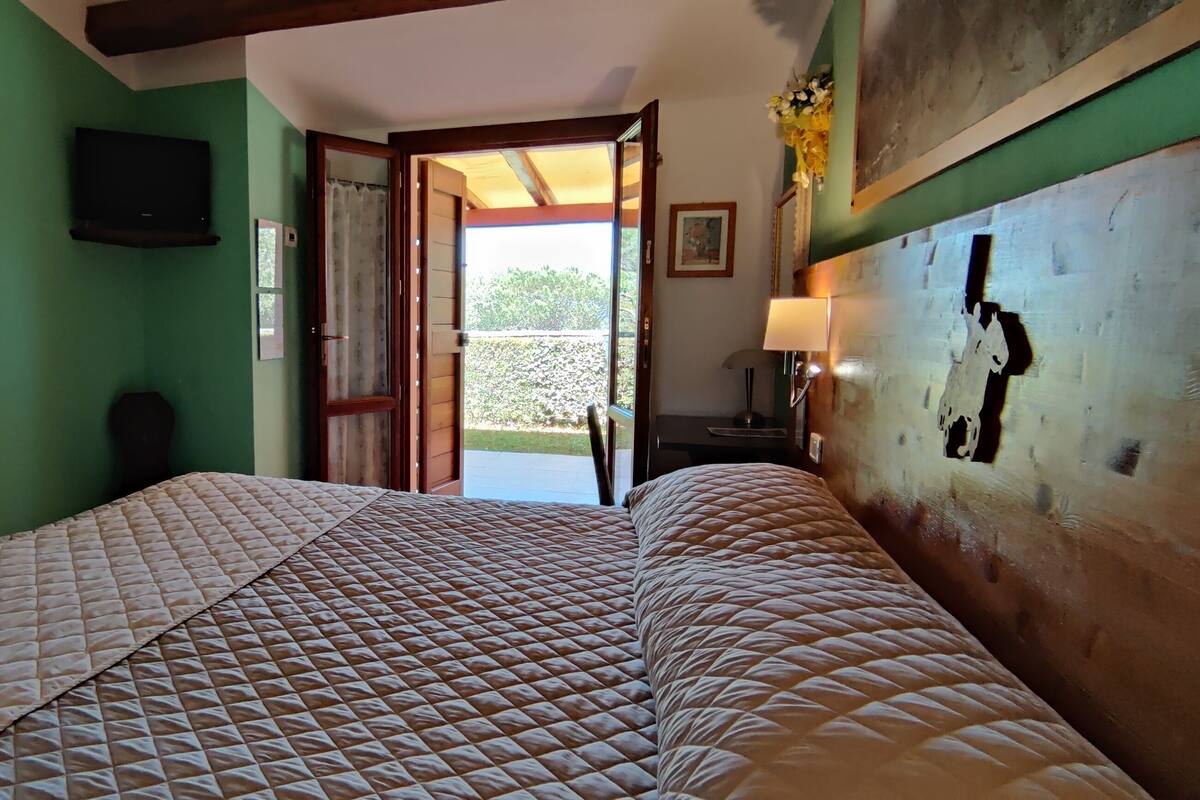 Ein Schlafzimmer mit einem Bett, einem Fernseher und einer Tür, die auf einen Balkon führt.