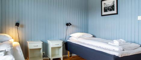 Une chambre avec un lit simple, une table de chevet et une commode.