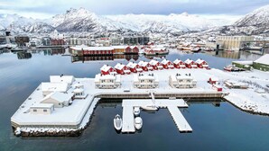 A waterfront property with multiple buildings, a dock, and a snow-covered landscape with mountains in the background.