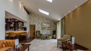 A hotel lobby with a bar area, seating arrangements, and a patterned wall.
