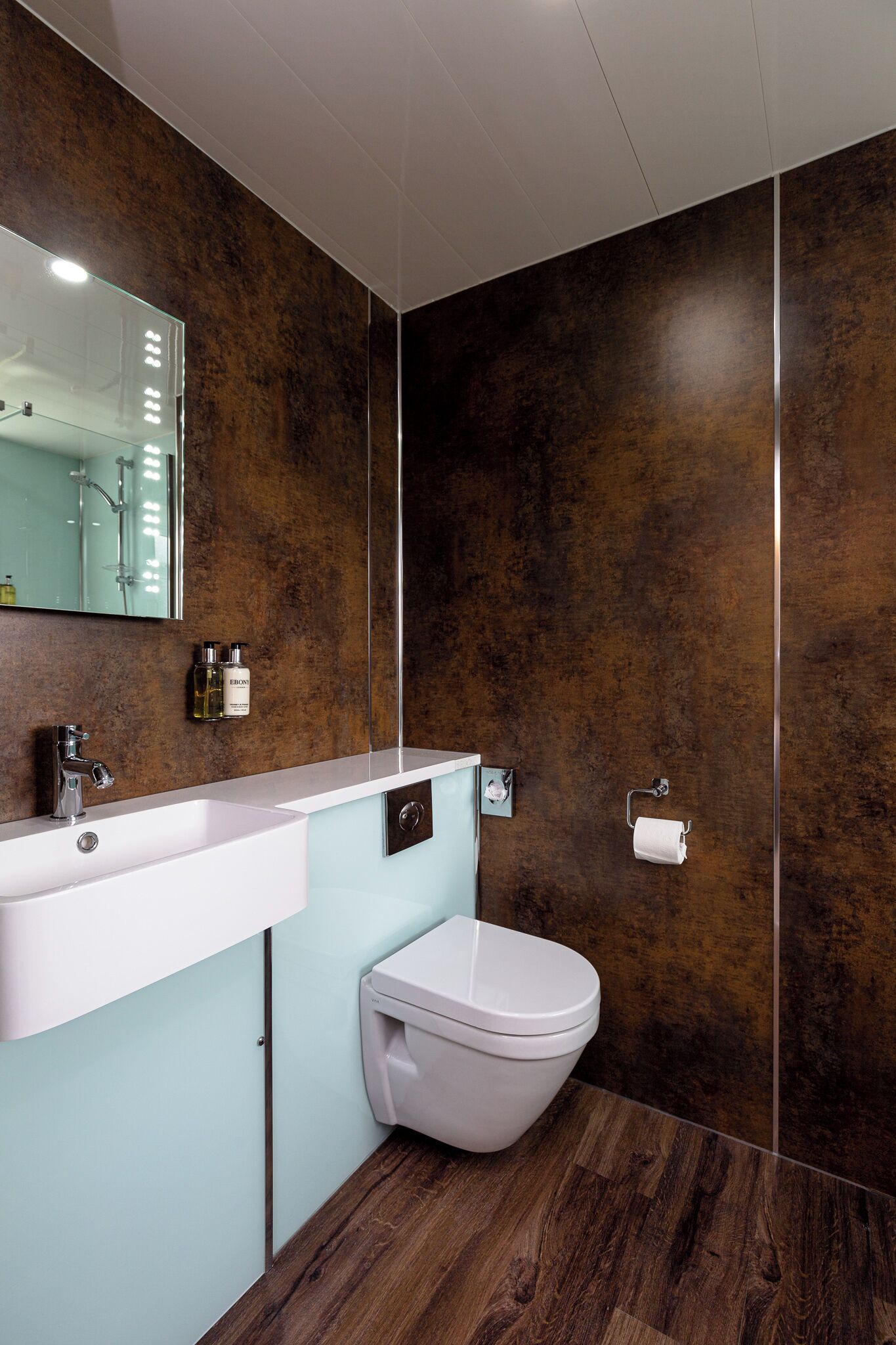 A modern bathroom with a white sink, a toilet, and a large mirror.