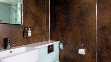 A modern bathroom with a white sink, a toilet, and a large mirror.