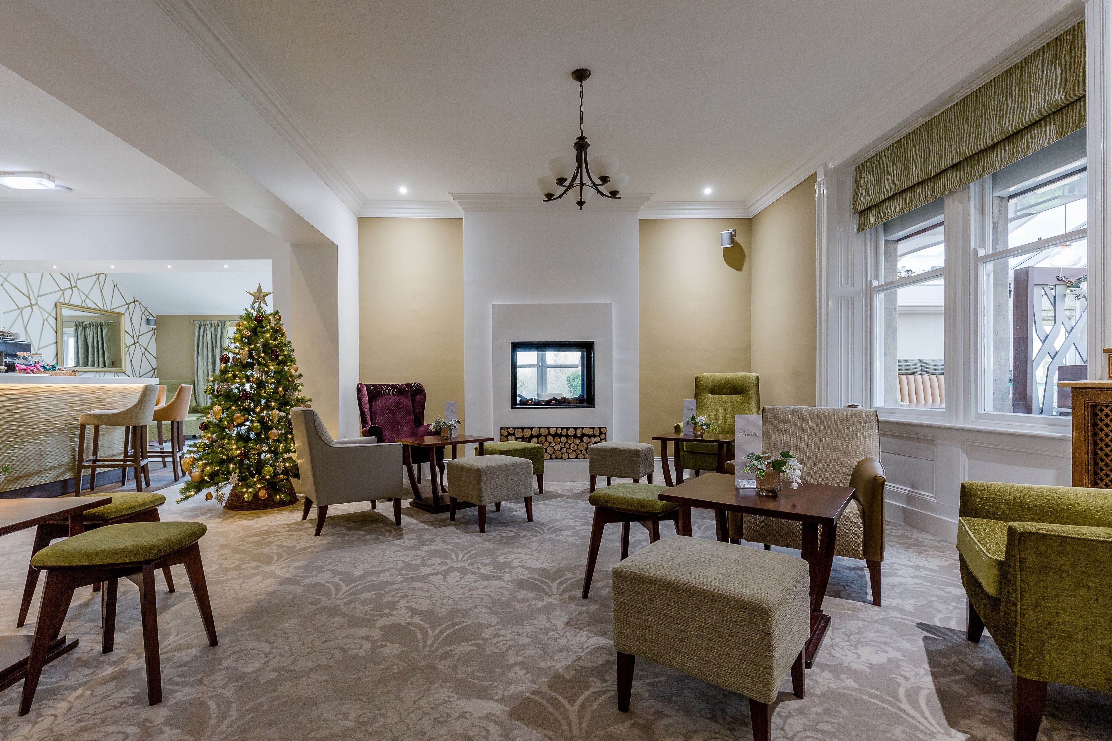 A spacious living area with a Christmas tree, comfortable seating, and a large window with a view.