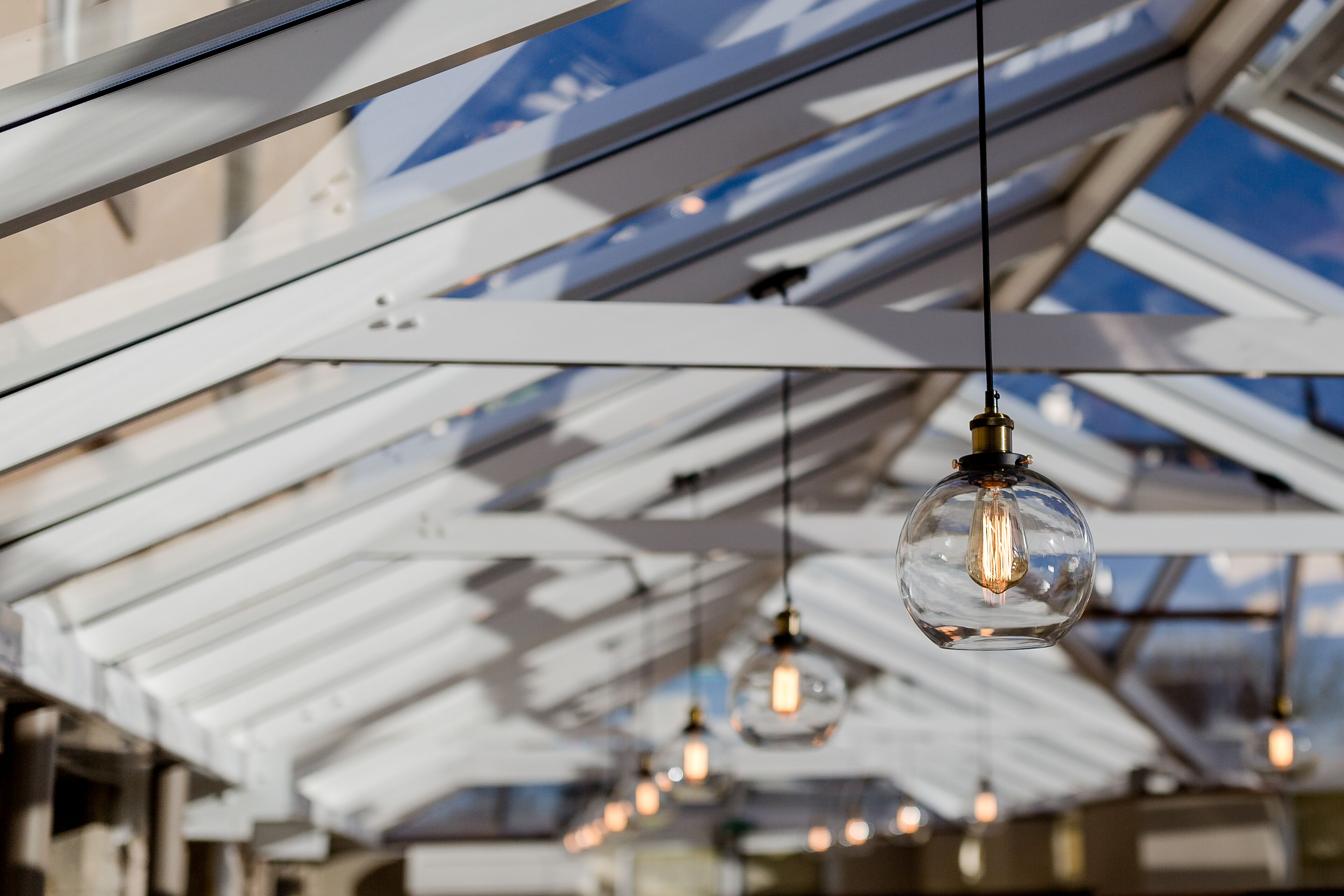 A modern interior with a glass ceiling and hanging light fixtures.