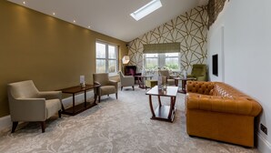 A spacious living room with a high ceiling, large windows, and a geometric wall design. - The Melbreak Hotel (Workington)
