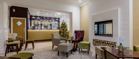 Un vestíbulo de hotel con mostrador de recepción, zona de estar y un árbol de Navidad.