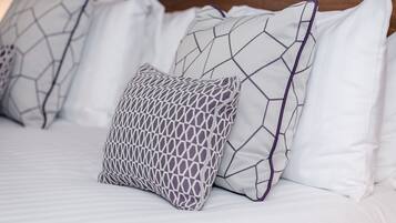 A bed with white bedding and patterned pillows.