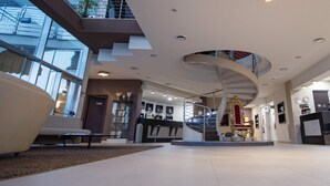A modern hotel lobby with a central staircase, a reception desk, and a seating area. - Mediterraneo Palace Depandance (Amantea)
