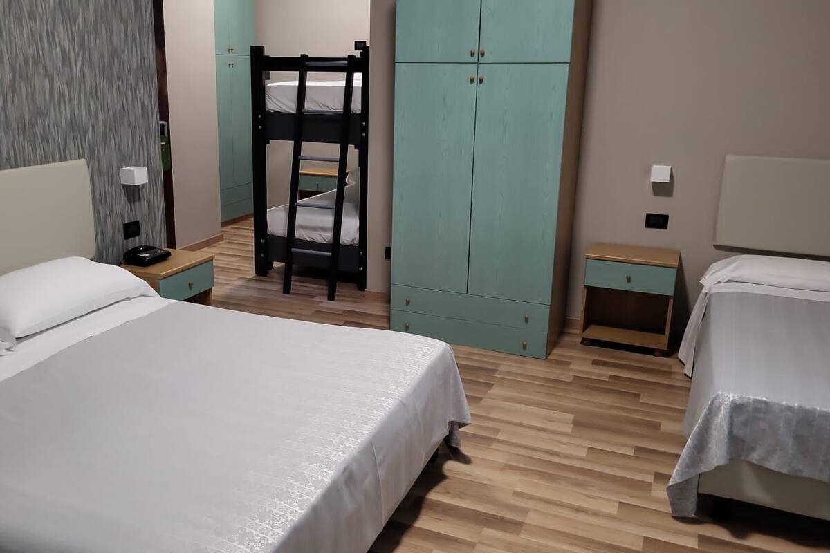Un dormitorio con dos camas, una litera, un armario y un escritorio.