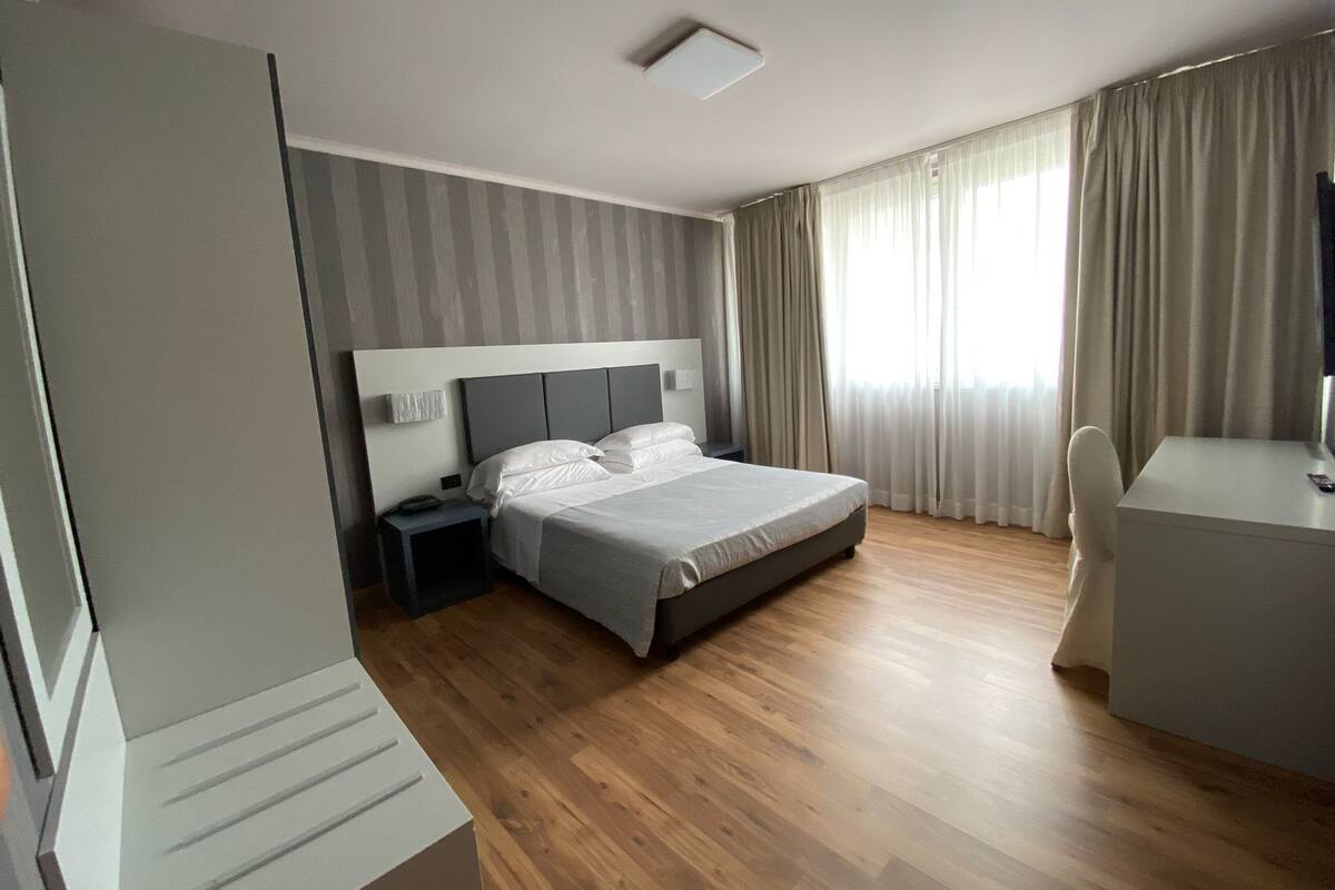 Una habitación de hotel moderna con una cama grande, un escritorio y una silla.