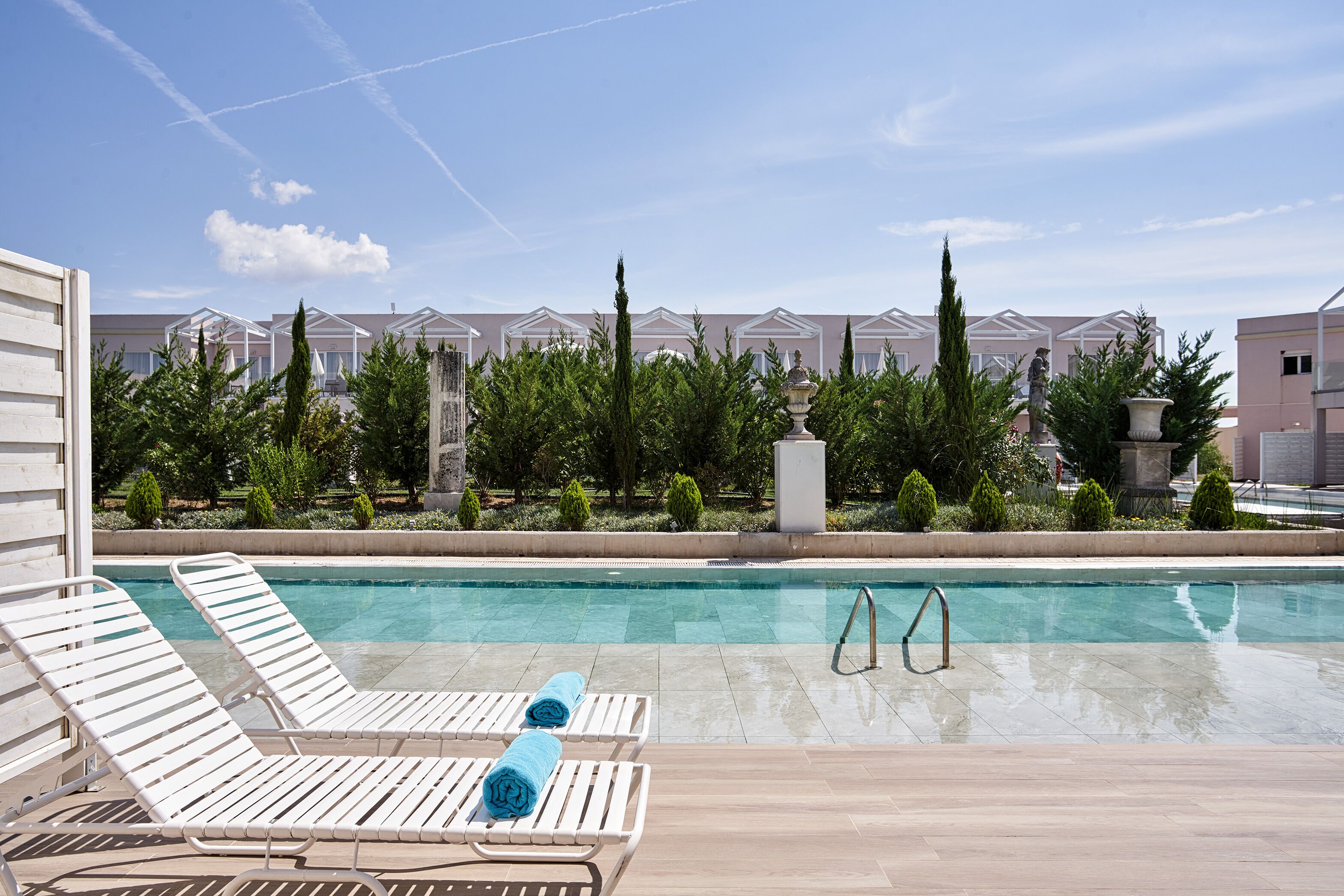 A pool area with white lounge chairs and a clear blue pool.
