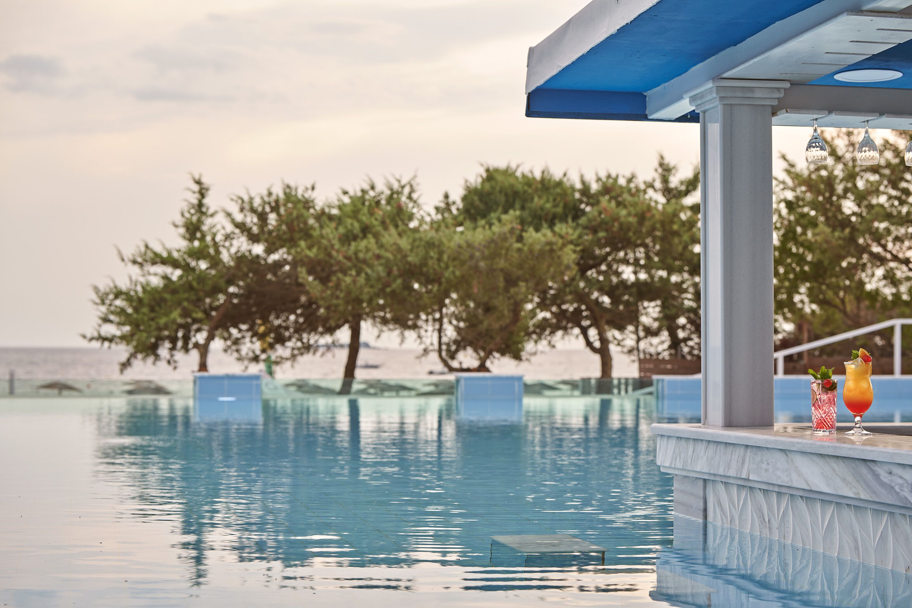 Un bar junto a la piscina con vista despejada a la piscina y árboles al fondo.