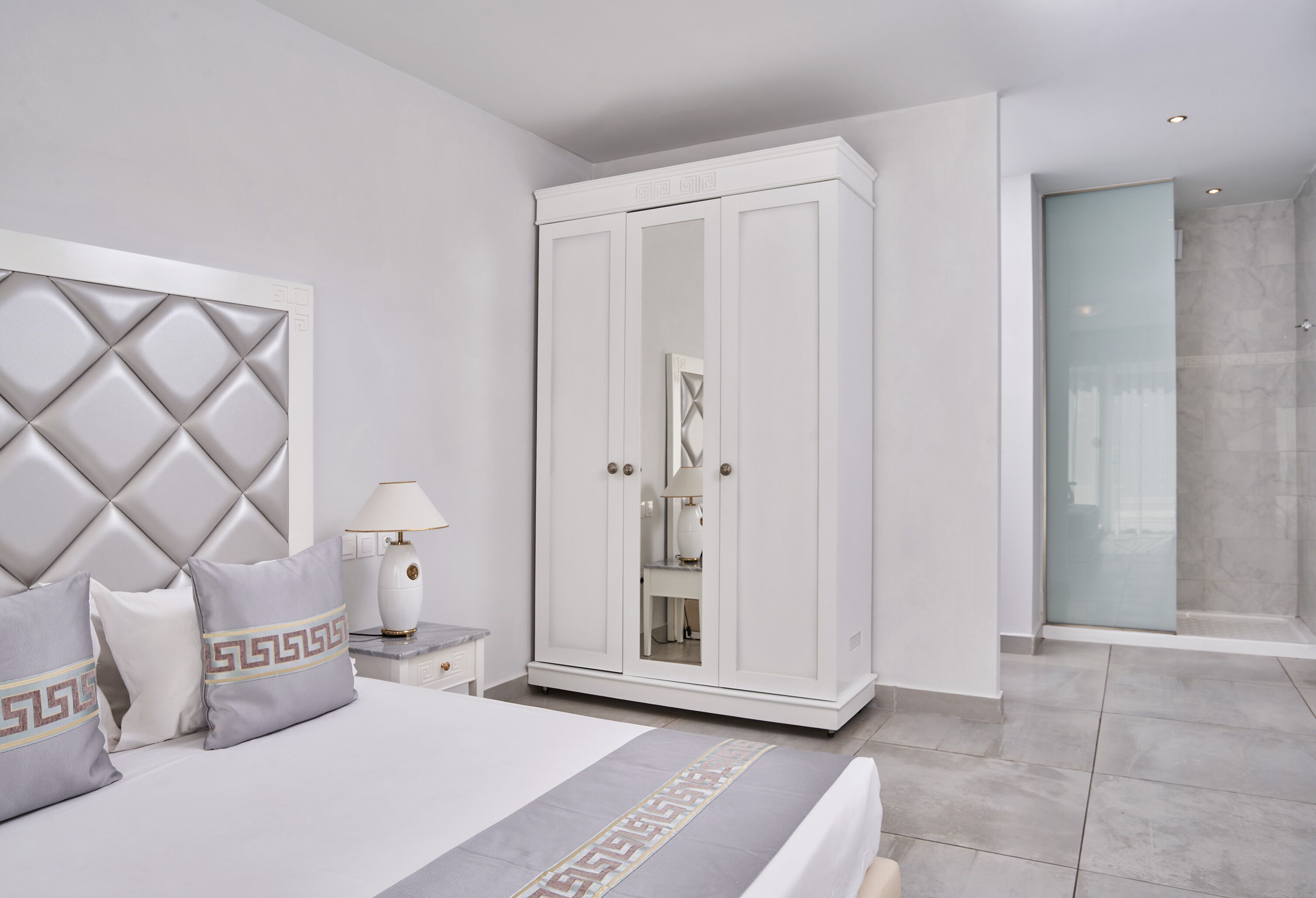 Een moderne slaapkamer met een groot bed, een kledingkast en een badkamer met een douchecabine.