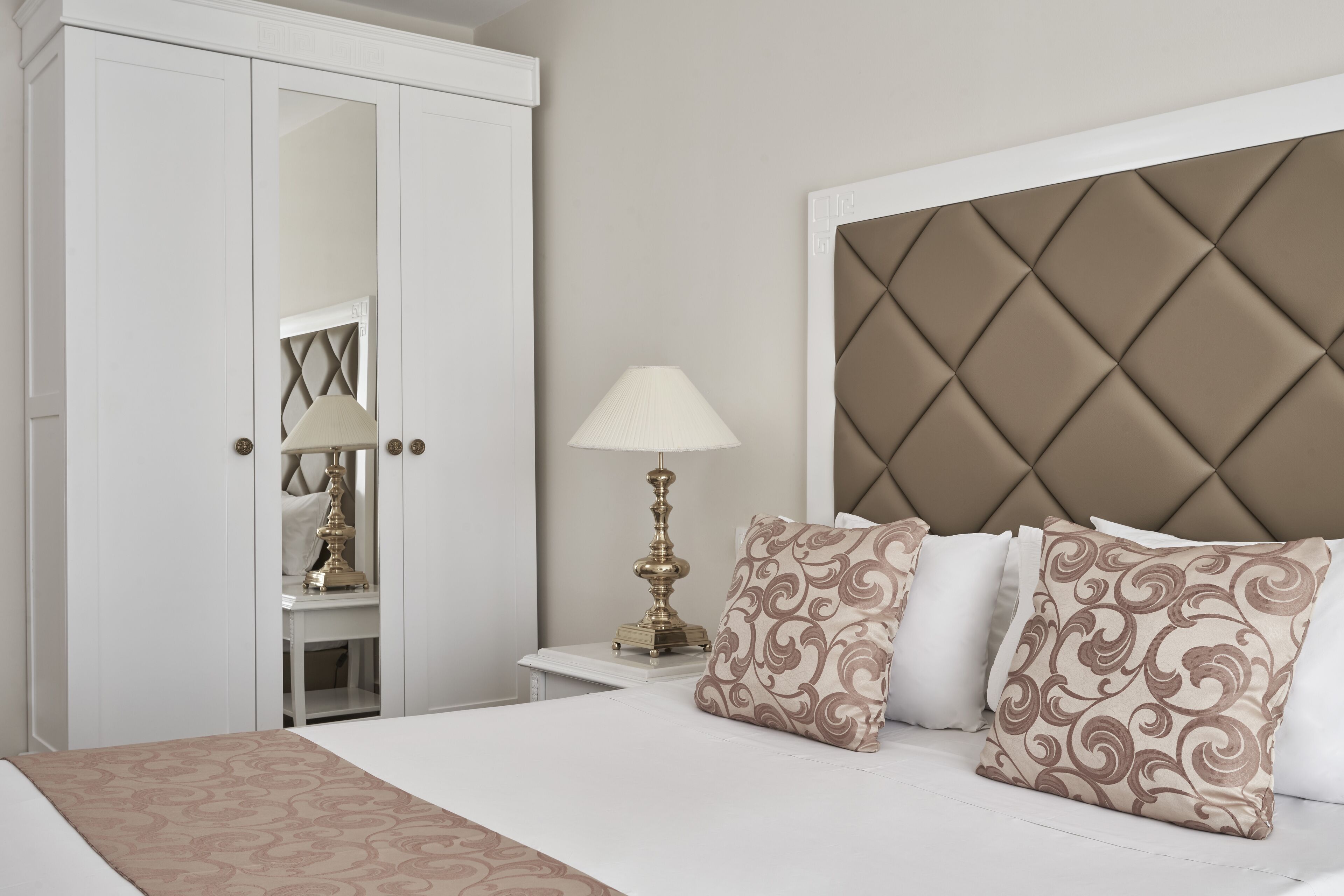 A bedroom with a bed, a nightstand, a lamp, and a wardrobe.