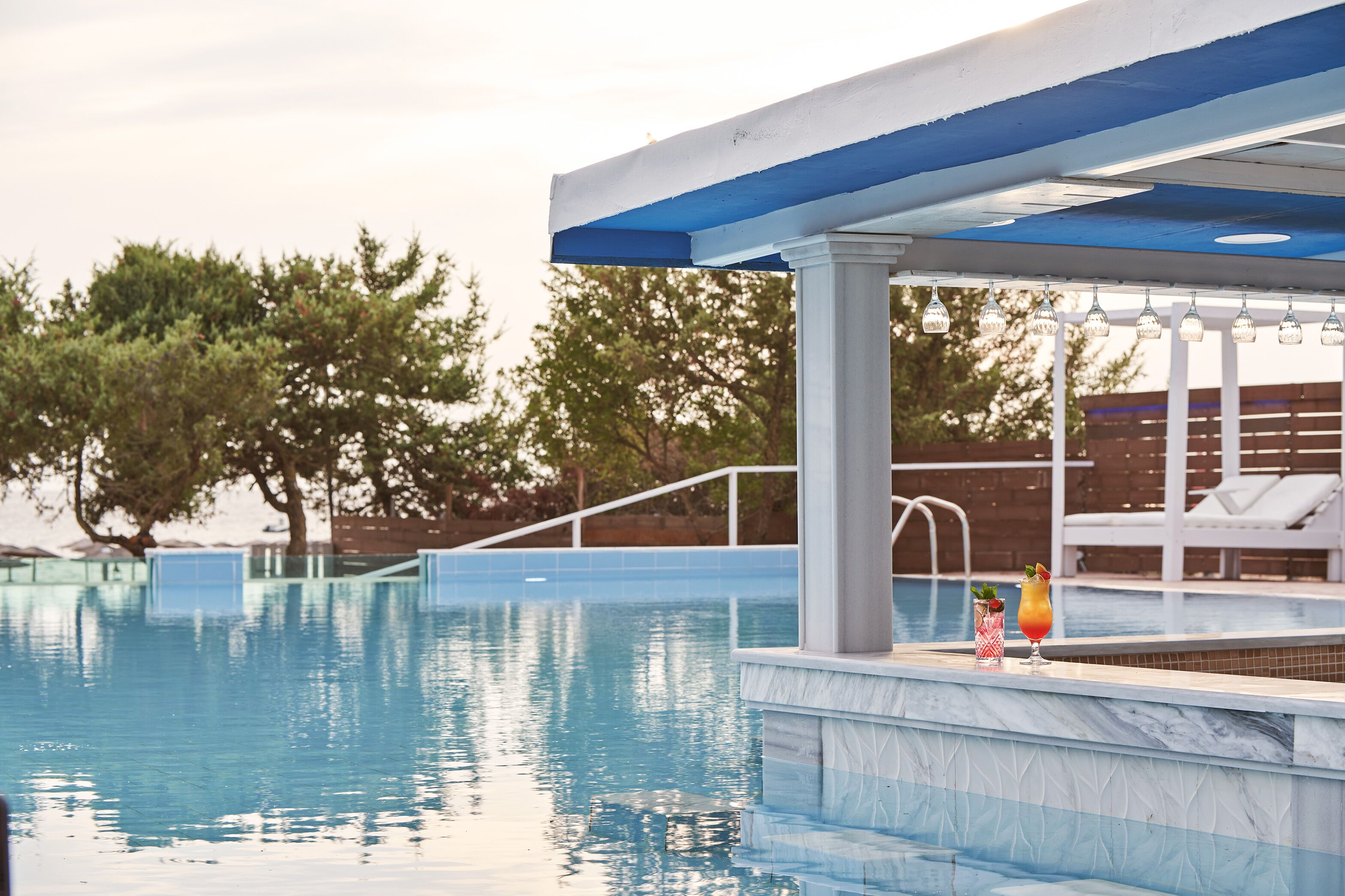 A swimming pool with a blue and white structure, surrounded by trees and a wooden fence.