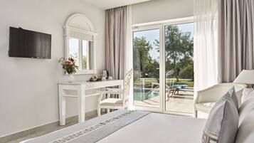 Quarto de hotel com cama, escrivaninha, poltrona, televisão e varanda com piscina.