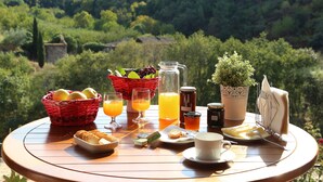 A breakfast table with a basket of fruits, a pitcher of juice, a bottle of honey, a cup of coffee, and a plate of croissants. - Quinta de Recião (Lamego)