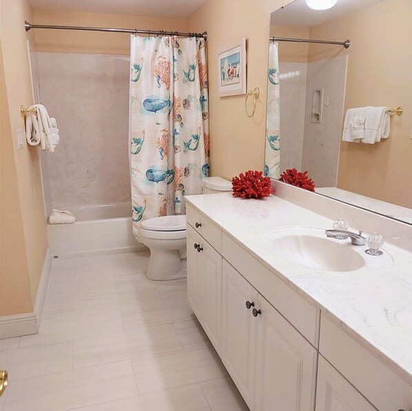 A bathroom with a bathtub, toilet, and a large mirror. - 1604 - Sunsets Every Night and Great Views! (Panama City Beach)
