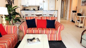 Ein Wohnzimmer mit gestreiften Sofas, einem weißen Couchtisch und einer Küche im Hintergrund.