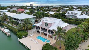 Una casa grande con piscina, muelle y vistas del barrio circundante.