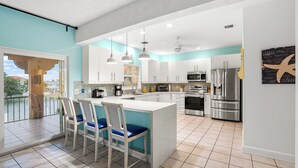 A modern kitchen with a central island, white cabinets, stainless steel appliances, and a view to the outside. - Beautiful 4 Bedroom, 3 Bath, Spacious Pool/SPA  Home with 200' wide Canal. (Marathon)