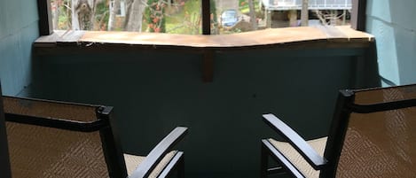 A room with two chairs facing a window overlooking trees with autumn foliage.