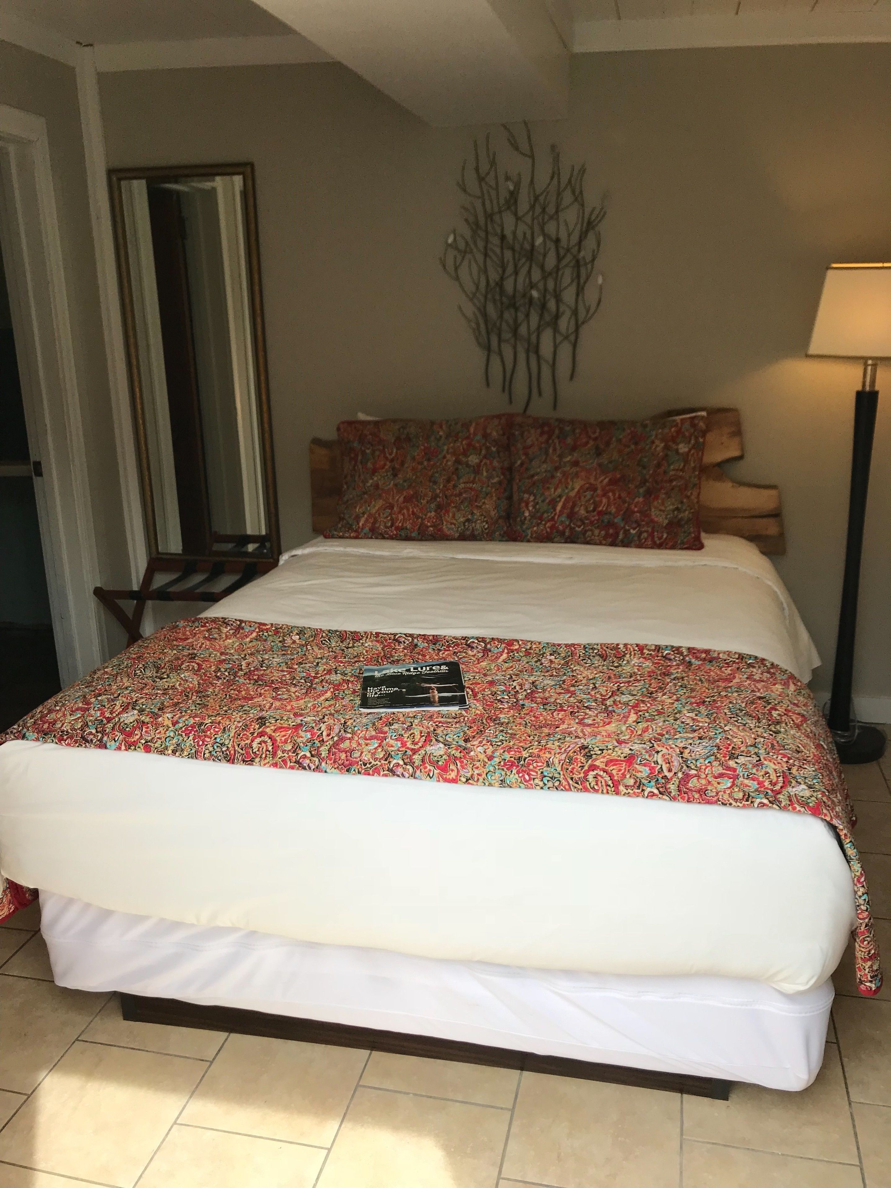 A bed with a floral-patterned bedspread and a black book titled 'Lyris' on it.