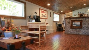 A rustic interior with a wooden chair, a table with a potted plant, and a stone fireplace. - The Riverside Lodge at Chimney Rock (Chimney Rock)