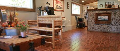 A rustic interior with a wooden chair, a table with a potted plant, and a stone fireplace.