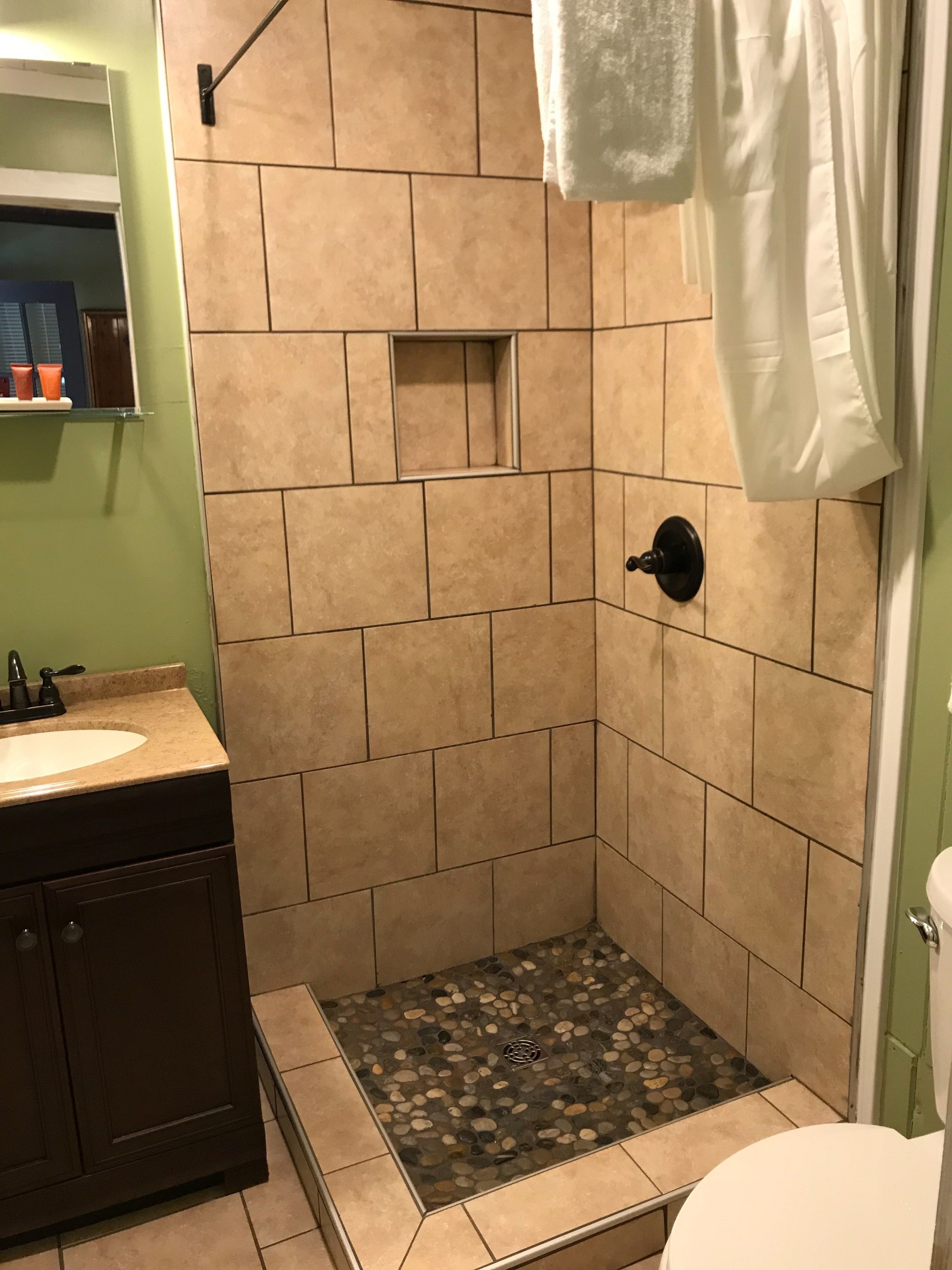 A bathroom with a shower area, a sink, and a toilet.