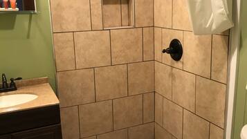 A bathroom with a shower area, a sink, and a toilet.