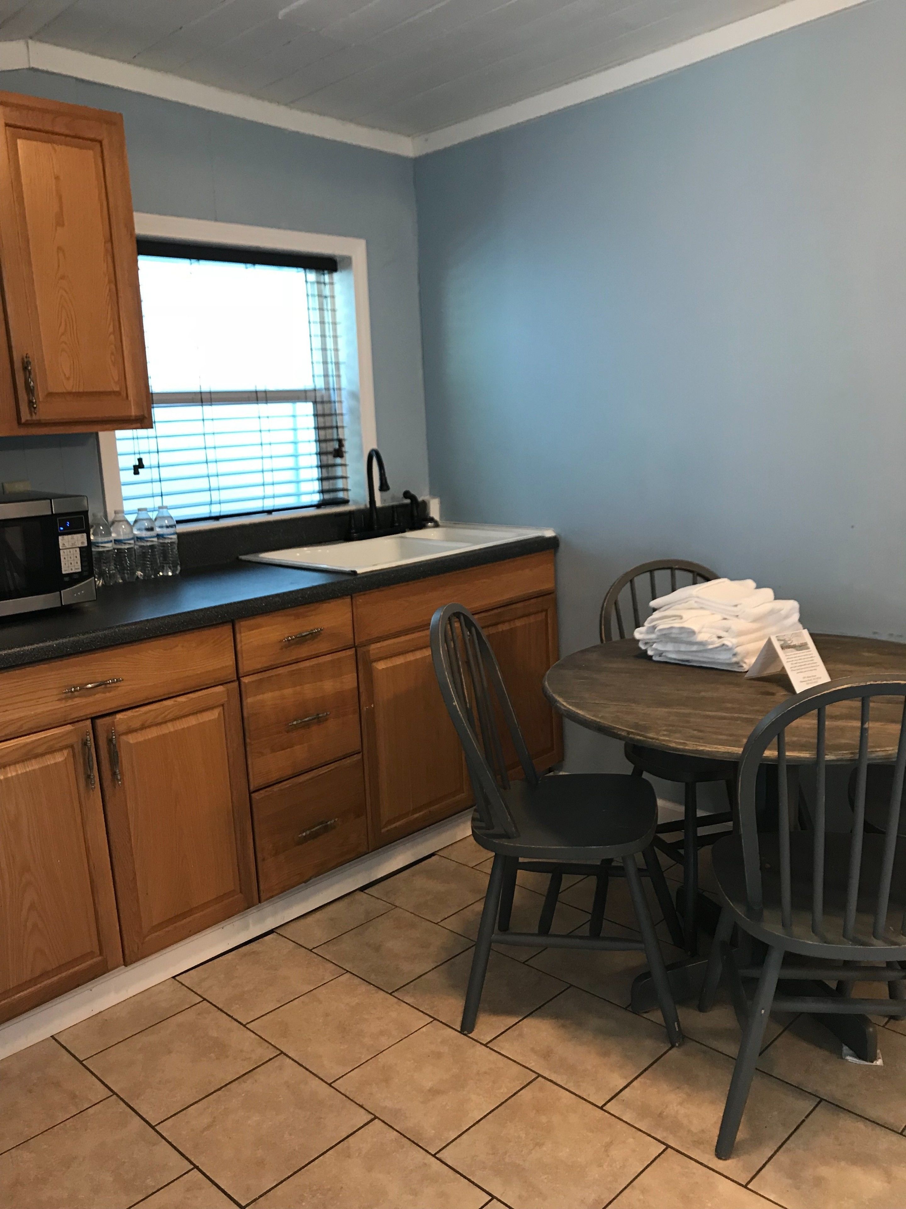 A kitchen with wooden cabinets, a sink, and a dining table with chairs.