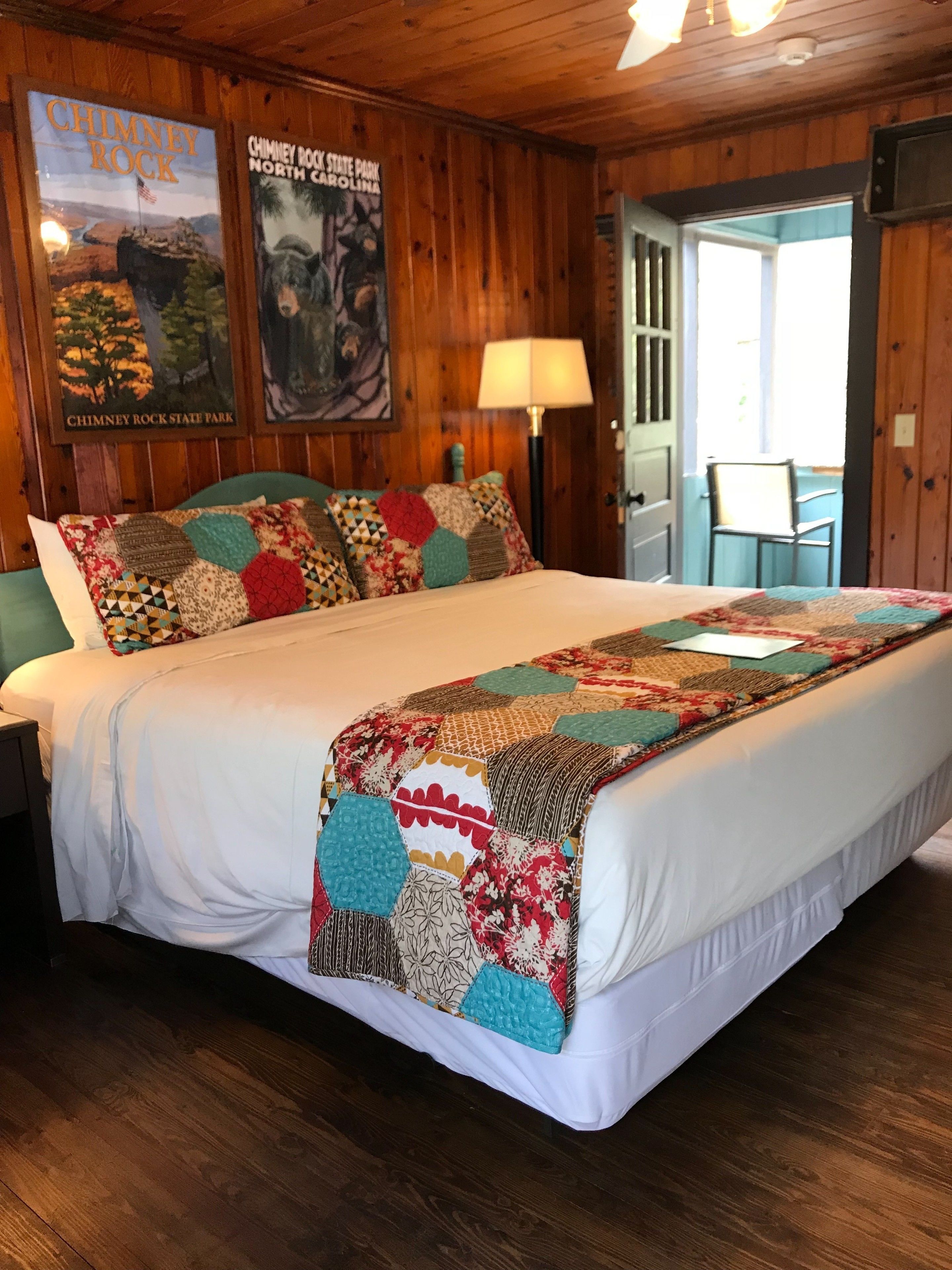 A wooden room with a bed, a lamp, and posters on the wall.