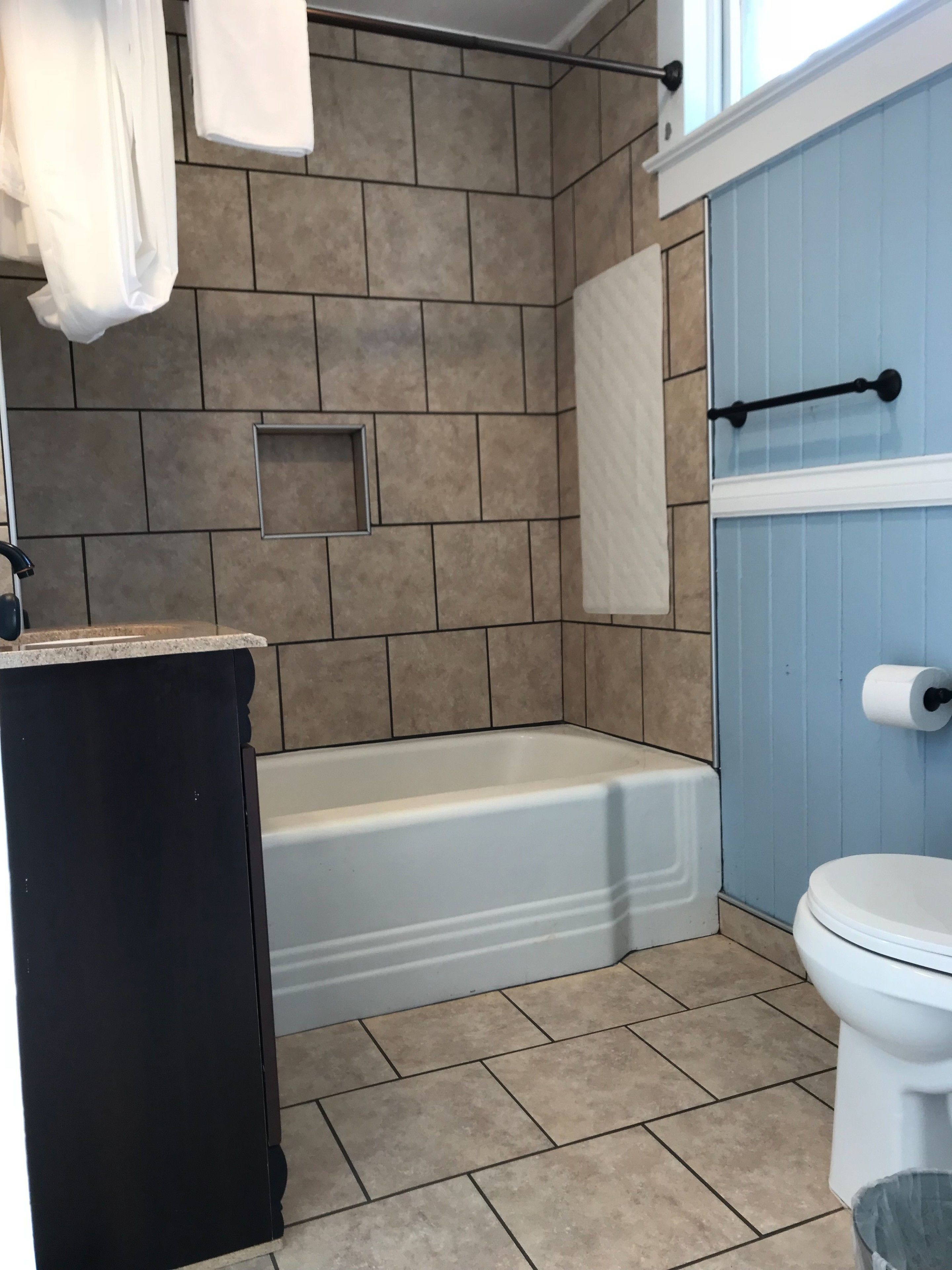 A bathroom with a bathtub, toilet, and a towel rack.