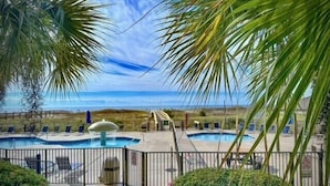 A pool area with two pools, a water fountain, and lounge chairs. - Phoenix 8 ~ Two Bedroom ~ 3rd FLOOR!!!! (Orange Beach)