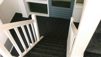 Eine Treppe mit weißen Geländern führt zu einem Raum mit dunklem Teppichboden.