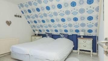 Un dormitorio con una cama, dos mesitas de noche, un aparador y una pared con estampado.