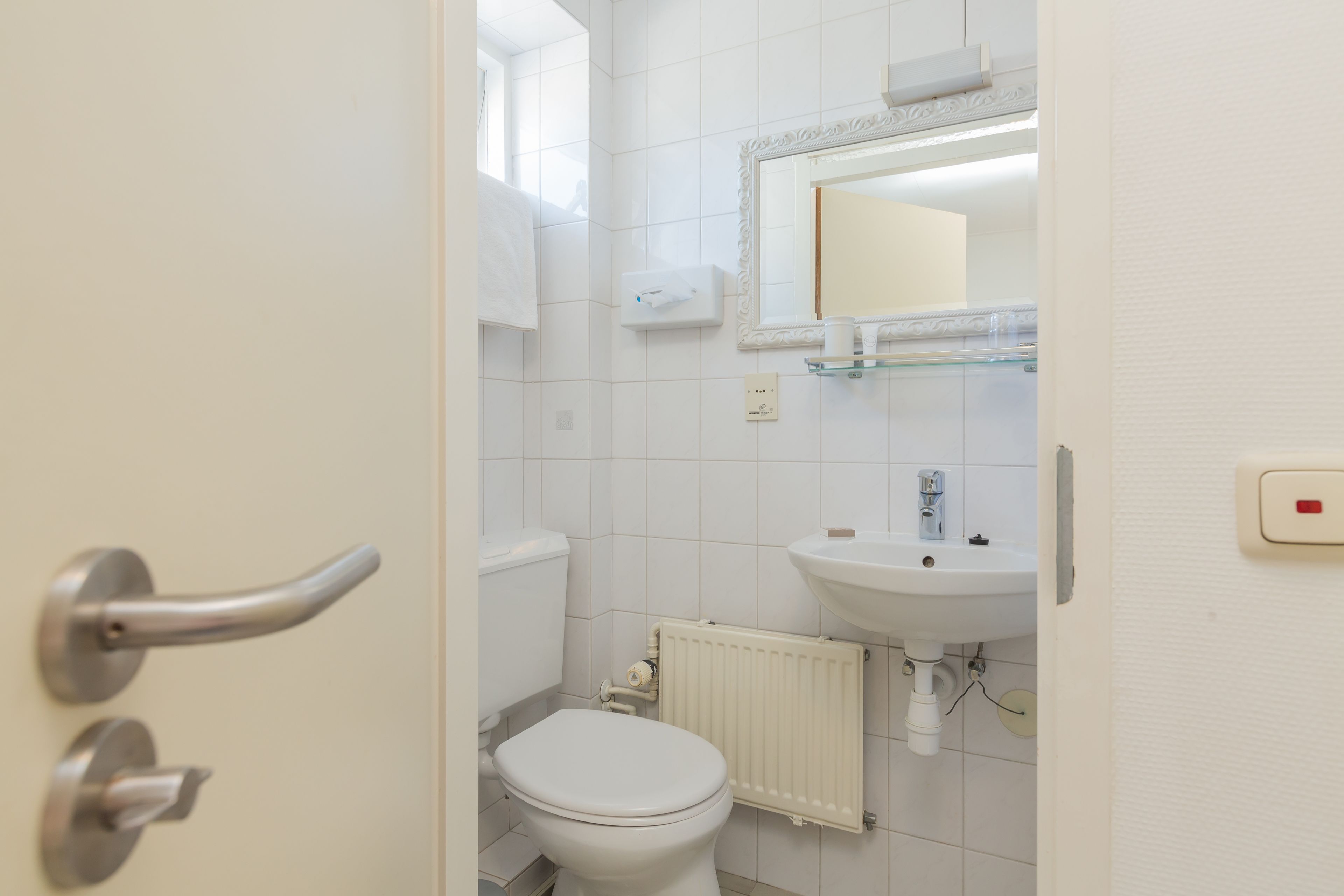 A bathroom with a toilet, sink, and mirror.