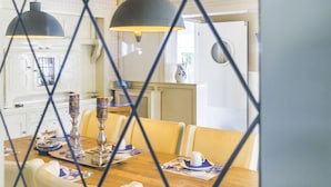 A dining area with a wooden table, yellow chairs, and pendant lights. - Pirombo Bed & Breakfast (Noordwijk)