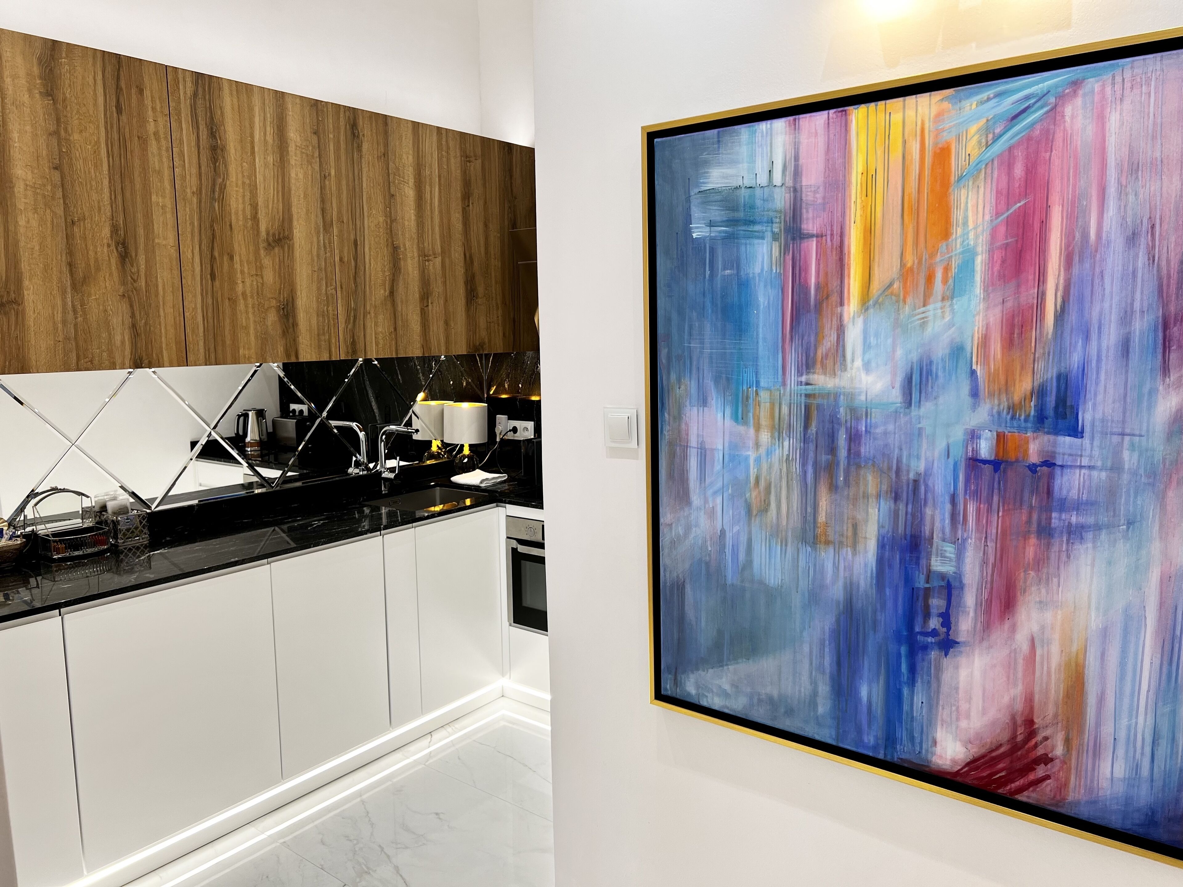 Een moderne keuken met witte kasten, een zwart aanrecht en een houten accentmuur.