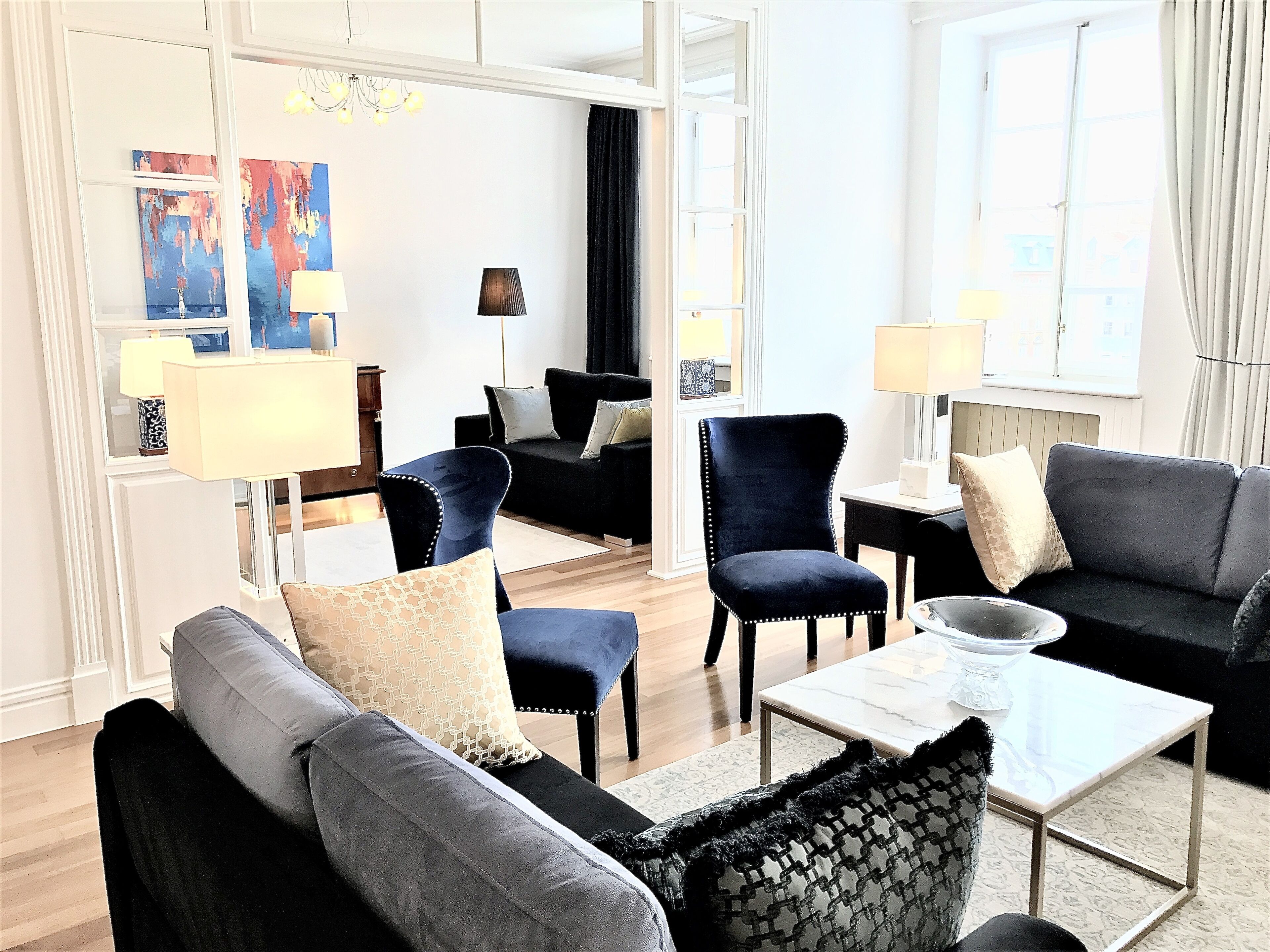 A modern living room with a sofa, armchairs, a coffee table, and a lamp.